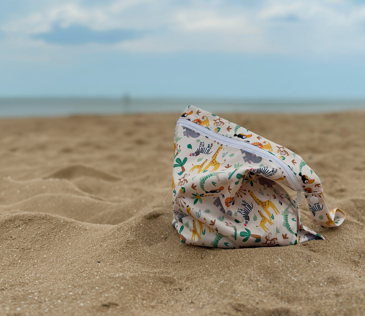 Folded fabric bag with animal prints on a sandy beach