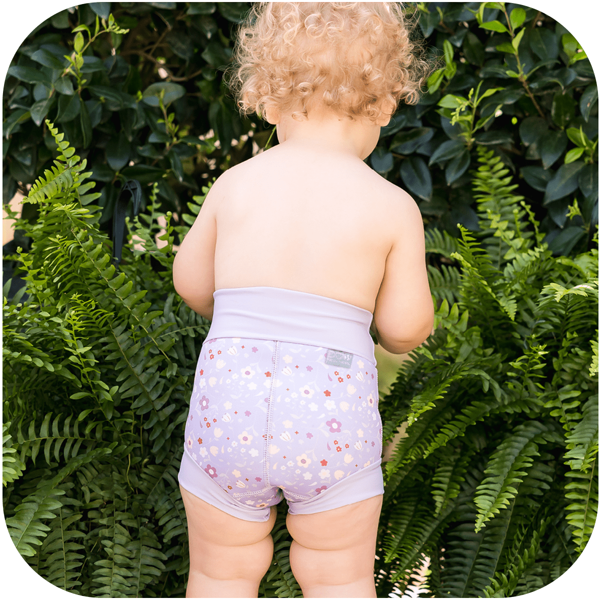 Happy Nappy Duo on little girls stood up infront of green flowers